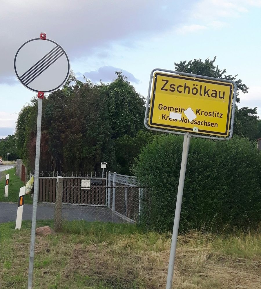 Ortseingangsschild Zschölkau, daneben ein Verkehrszeichen „Ende aller Streckenbeschränkungen“
